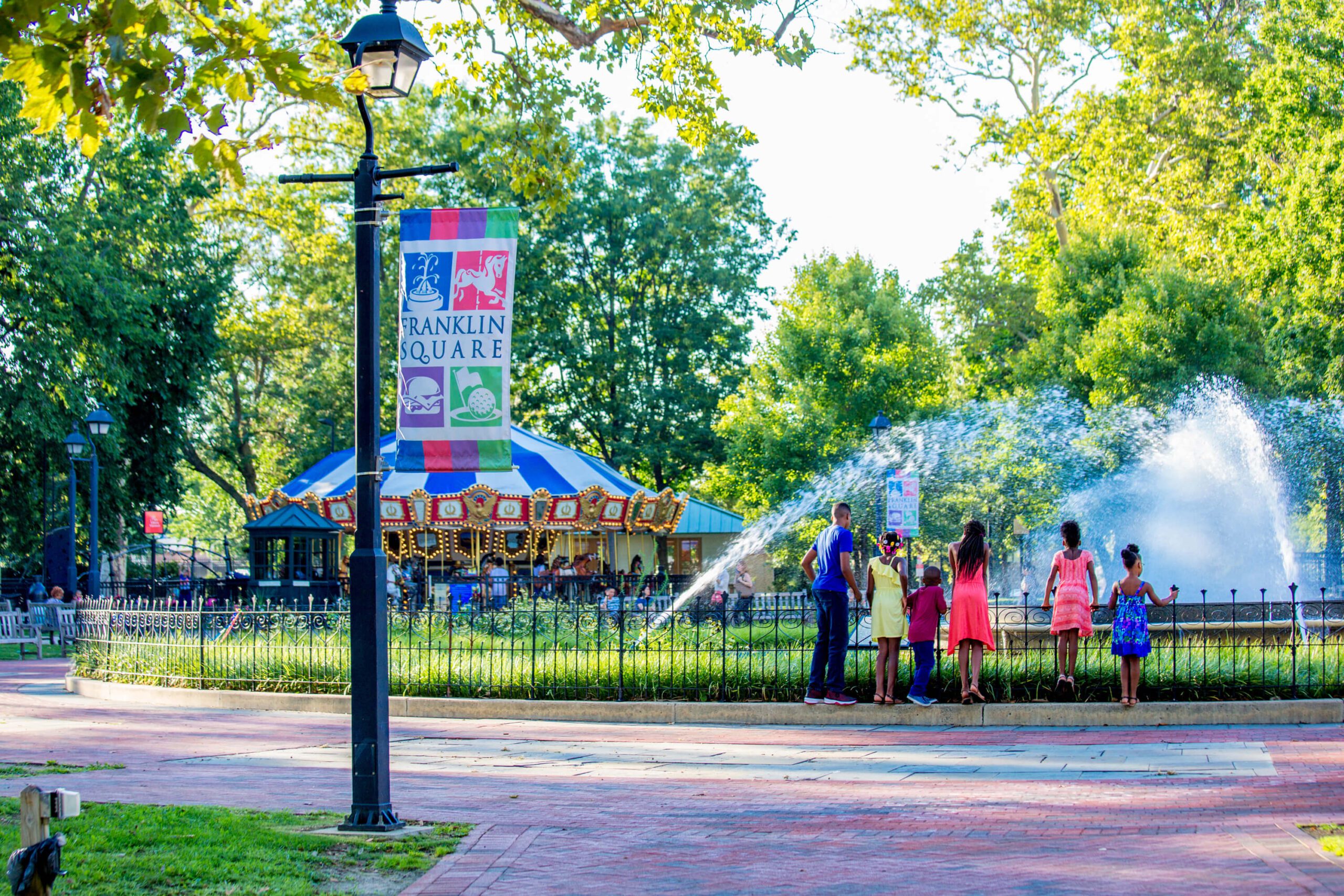Photo of a family in the park near a fountain and a carousel.
