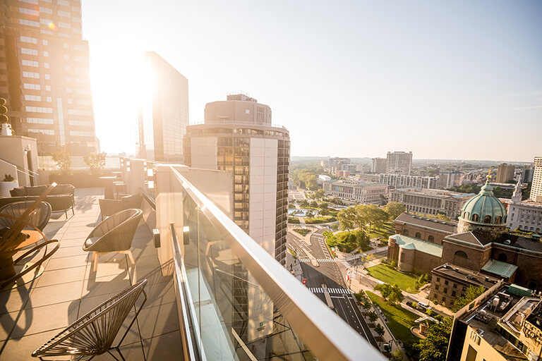 The sun shines on a balcony overlooking the Cathedral Basilica of Saints Peter and Paul and the city's streets below.