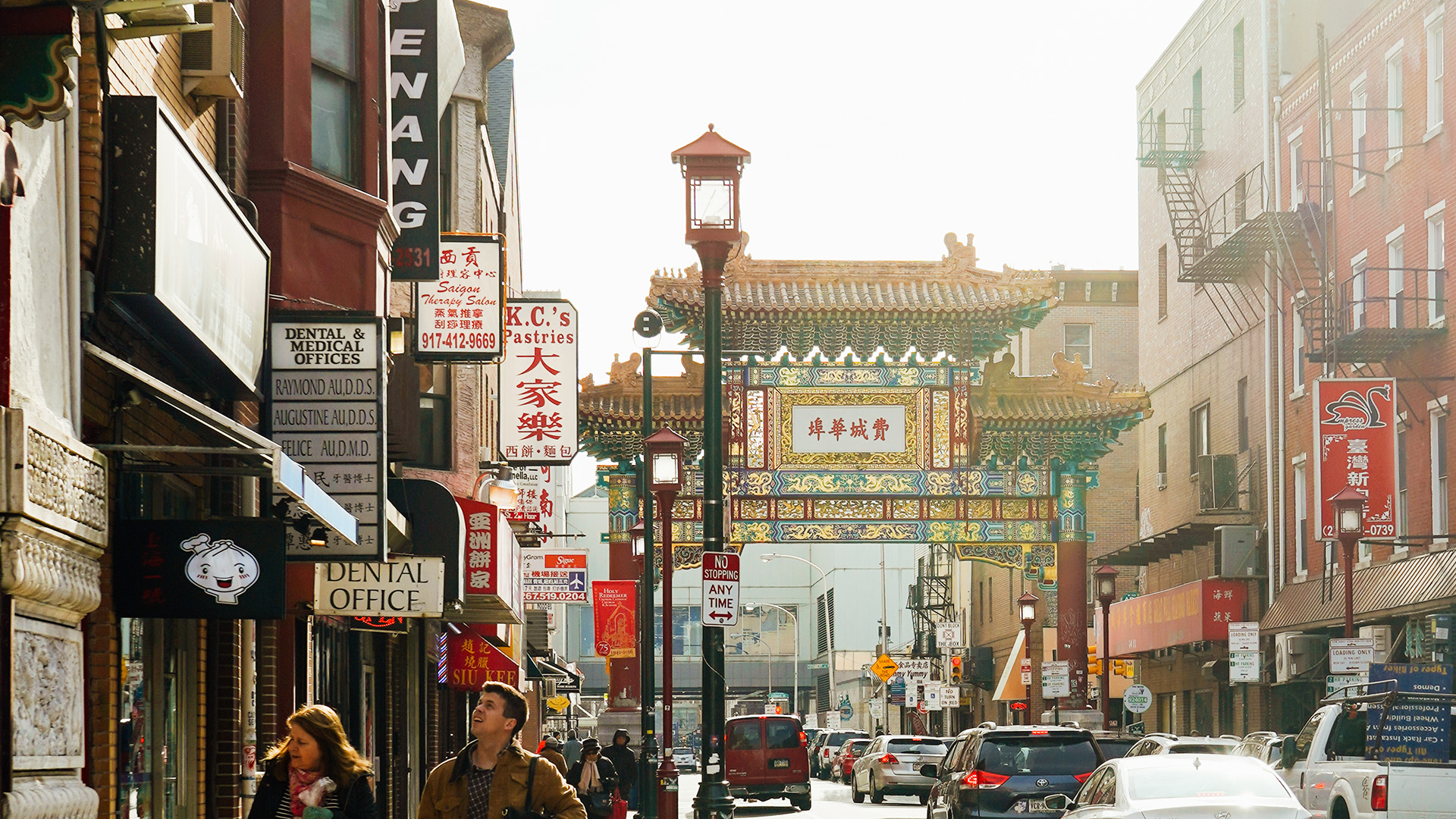 A street in Chinatown with signs for Chinese businesses and a large decorative archway.