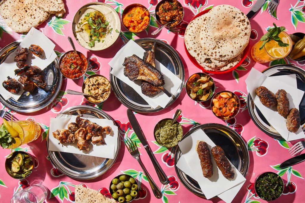 A pink table full of Mediterranean dishes.