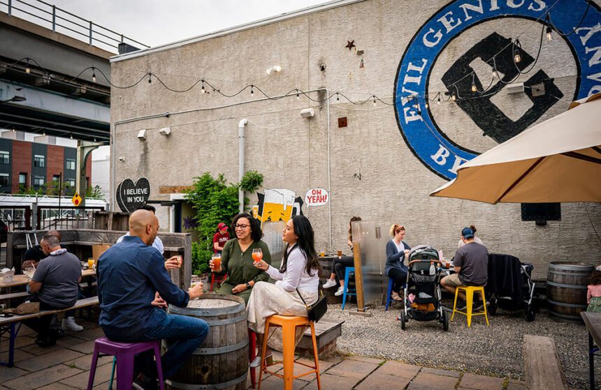 Many people enjoy the outdoor patio at Evil Genius Brewing, drinking beers and socializing.