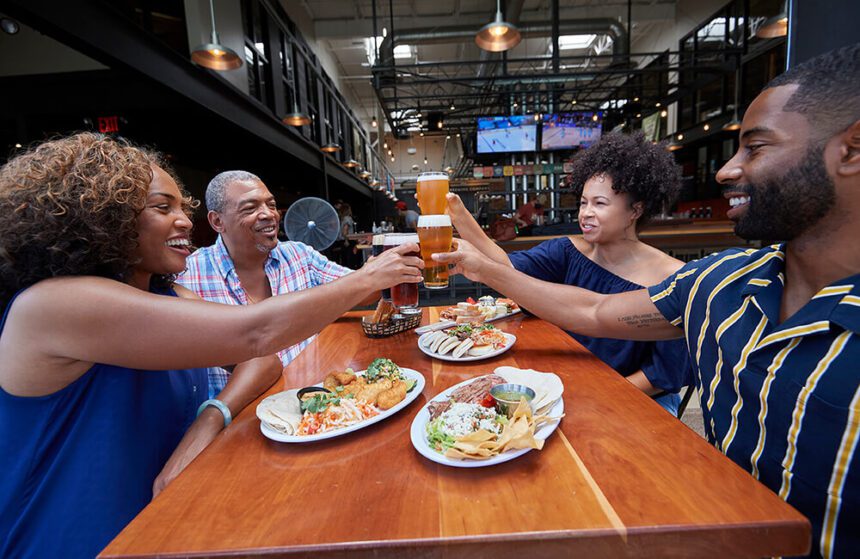 Four people sitting at a table drinking beers