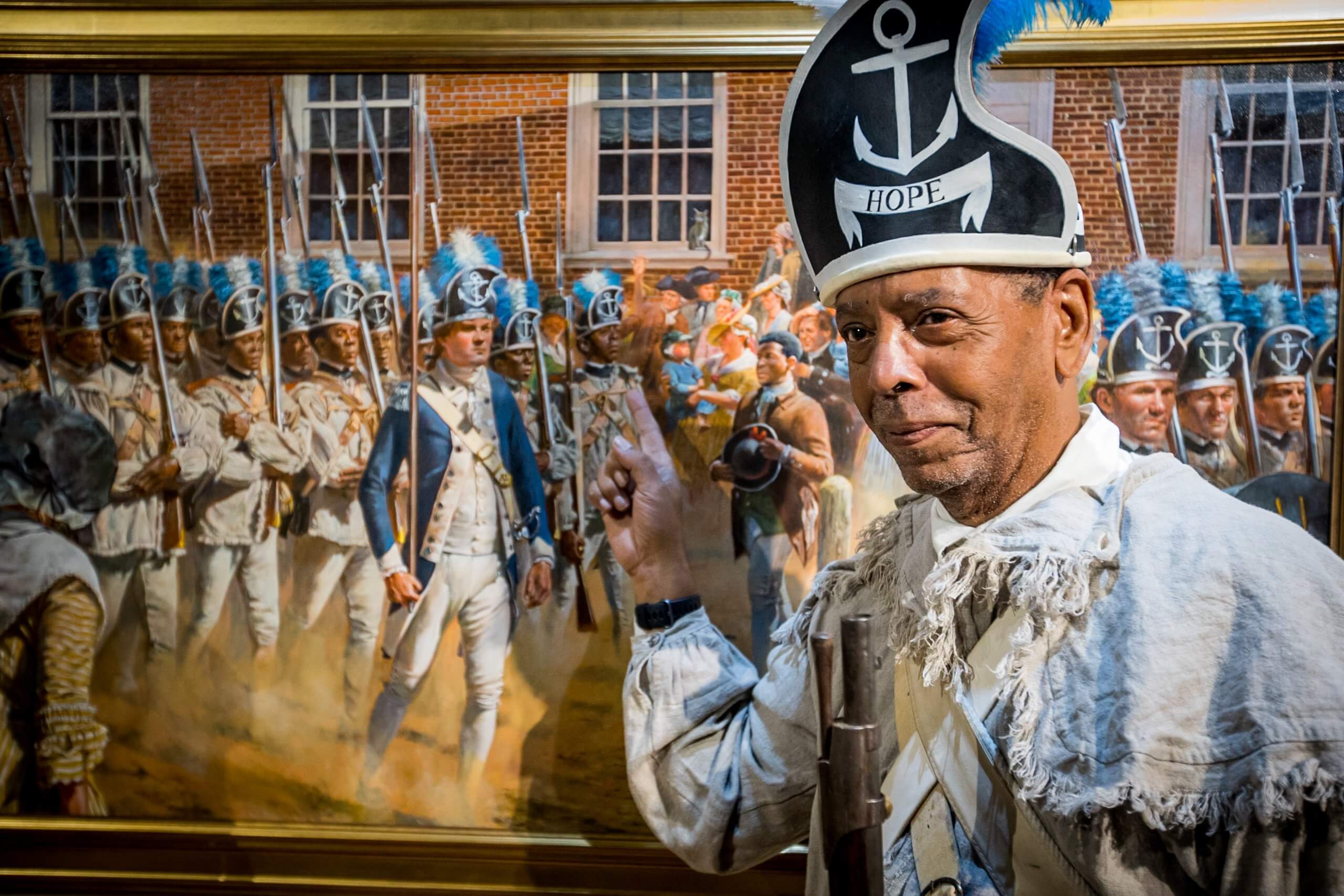 Man poses in front of a painting inside the Museum of the American Revolution