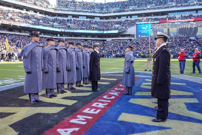 Members of both the Army and Navy are shown standing in the middle of a football field before the start of the Army-Navy football game at Lincoln Financial Field.