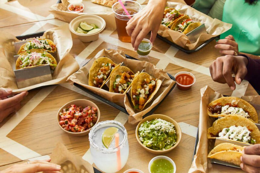 A table full of tacos, salsa, and guacamole.