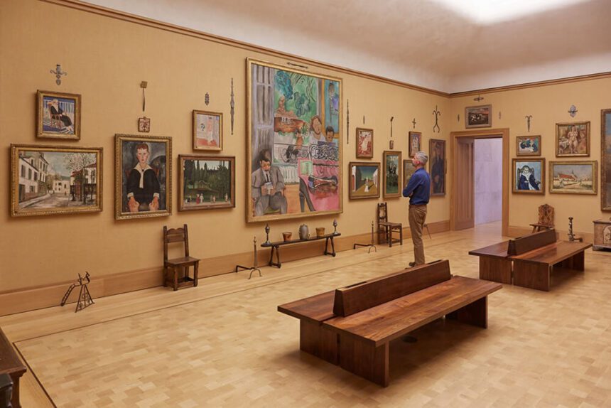 A person stands in a room full of paintings, admiring the artwork.