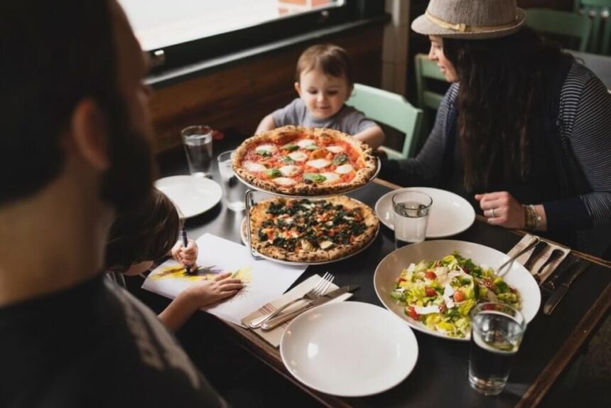 Two parents and a child enjoy pizza in a restaurant.