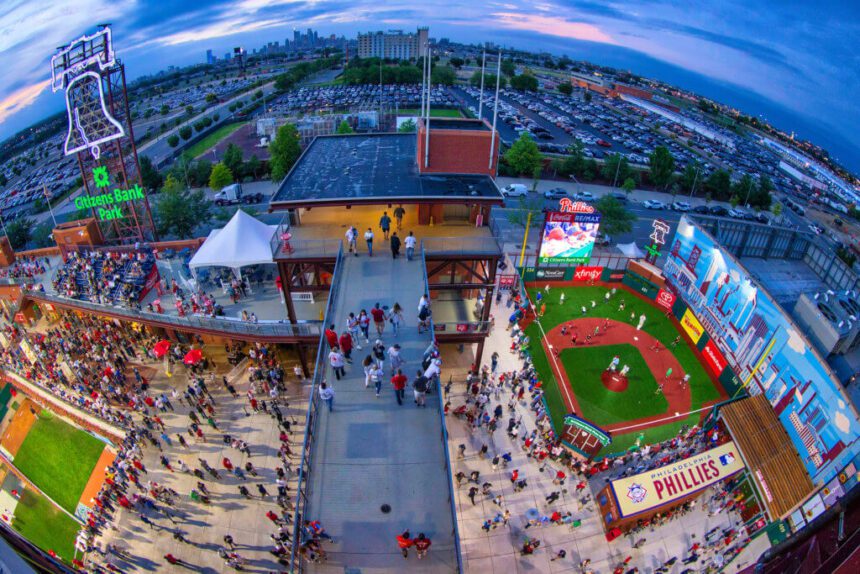 A large group of people gather near a baseball stadium