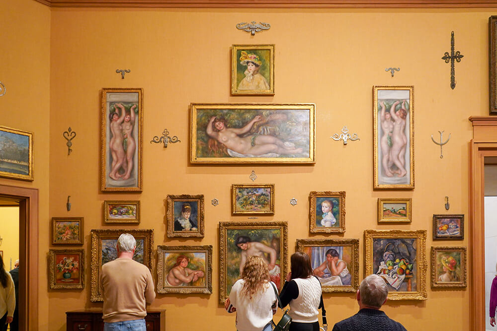 Four people stand in front of an array of paintings at the Barnes Foundation.