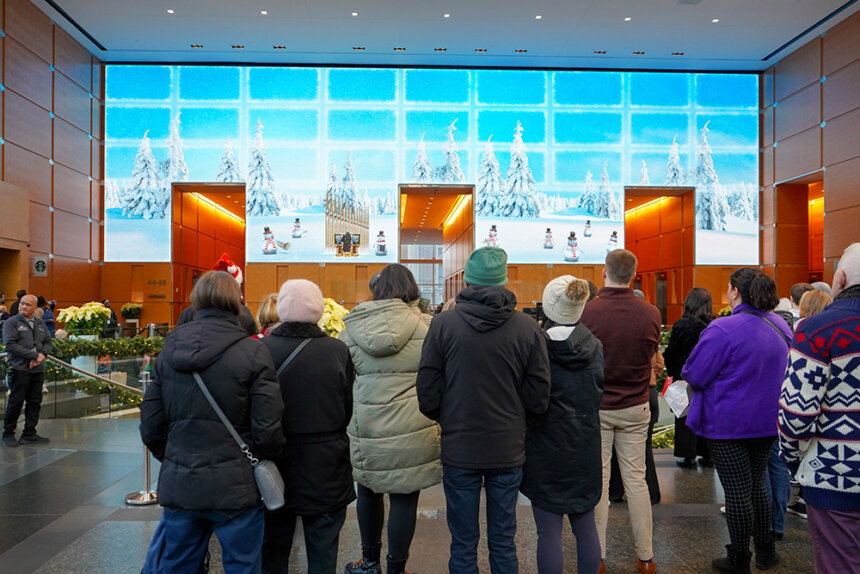 A group of people look at a festival screen in a lobby.