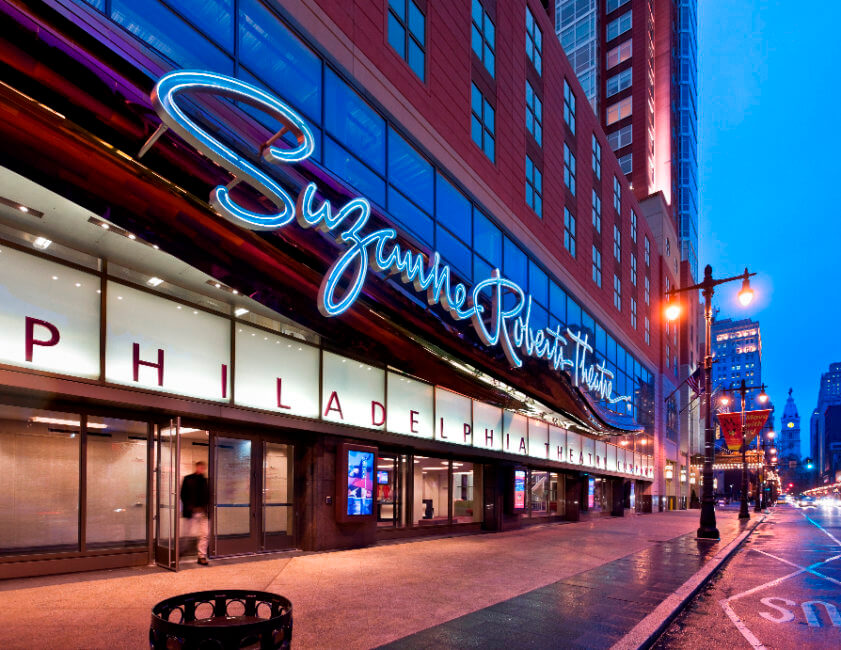 A building with a glowing sign that says Suzanne Roberts Theater.
