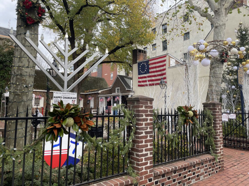 A large menorah sits in the front patio of a rowhome.