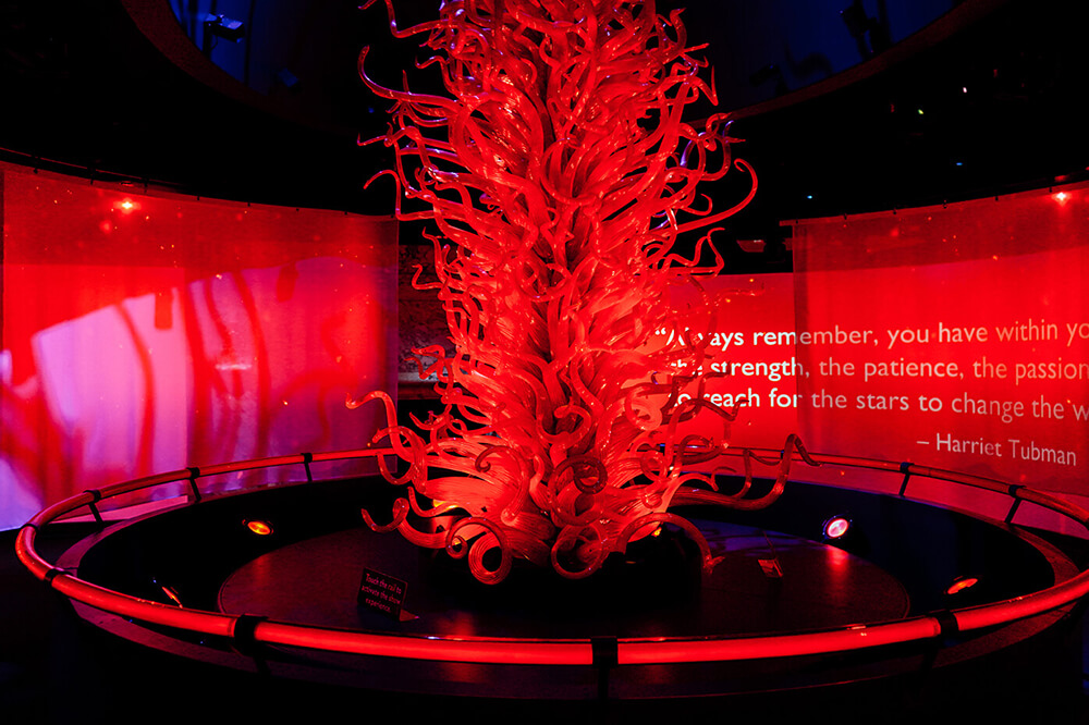 A glass sculpture with with twirling red ribbons of glass projecting toward the ceiling.