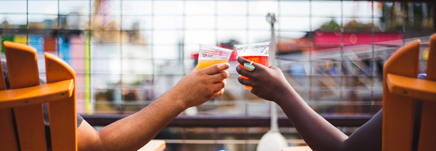 Two hands are shown holding drinks.