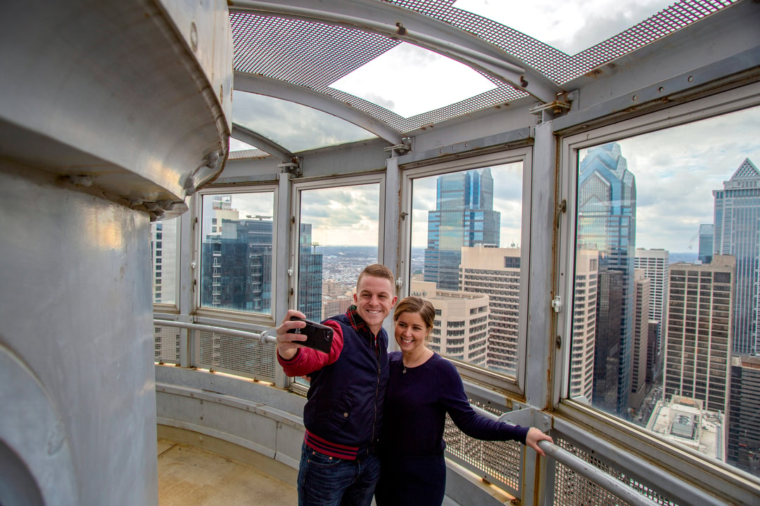 Couple standing in the tower of Philadelphia's city hall overlooking the city