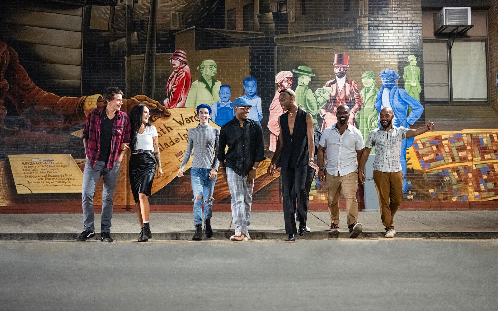 A group of people walking in front of a mural in Philadelphia.