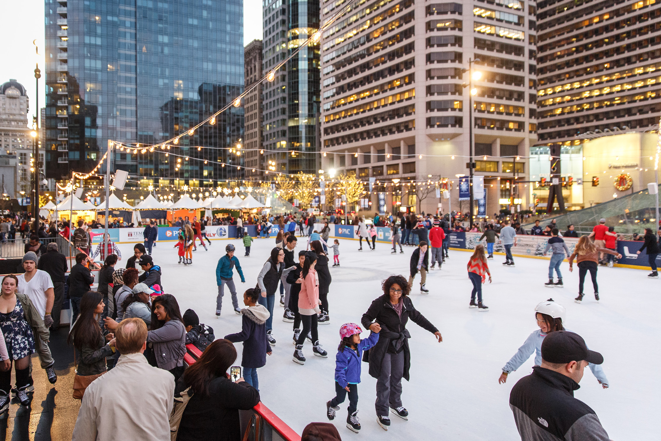 People skating on the ice rink at Dilworth Park beside Philadelphia City Hall