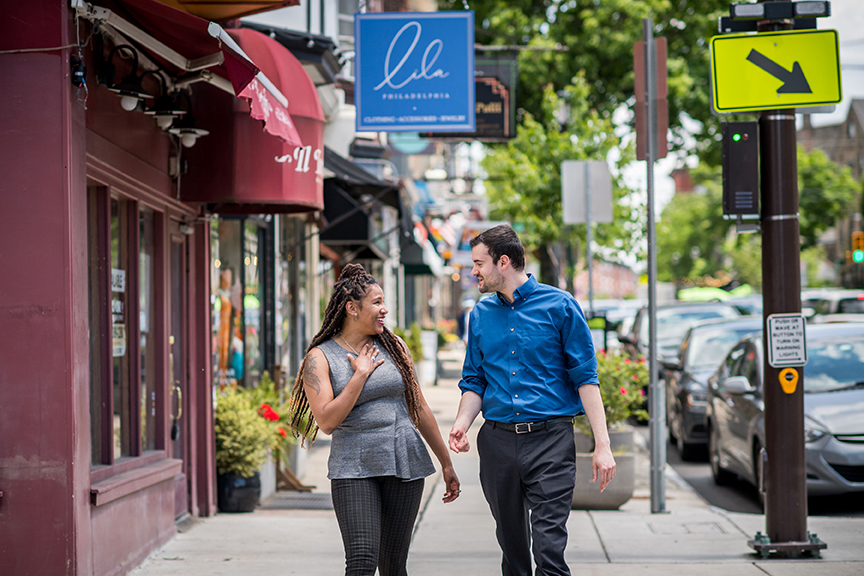 two people walk down a city street, laughing with each other.