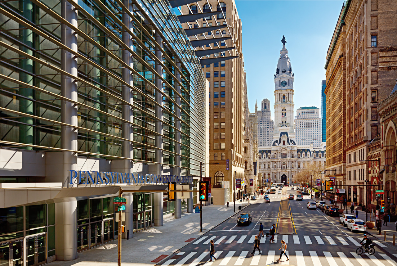 A city street with Philadelphia's City hall at the end of the street. To the left is the modern Pennsylvania Convention Center.