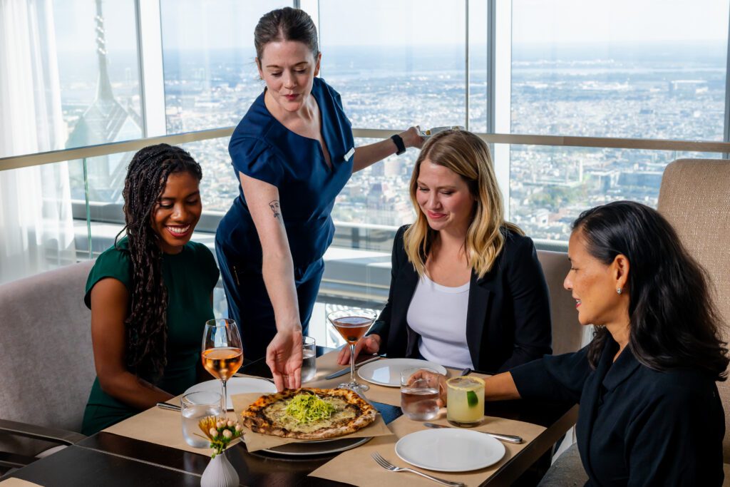 A waitress serving a plate of good to a group of patrons at SkyHigh.