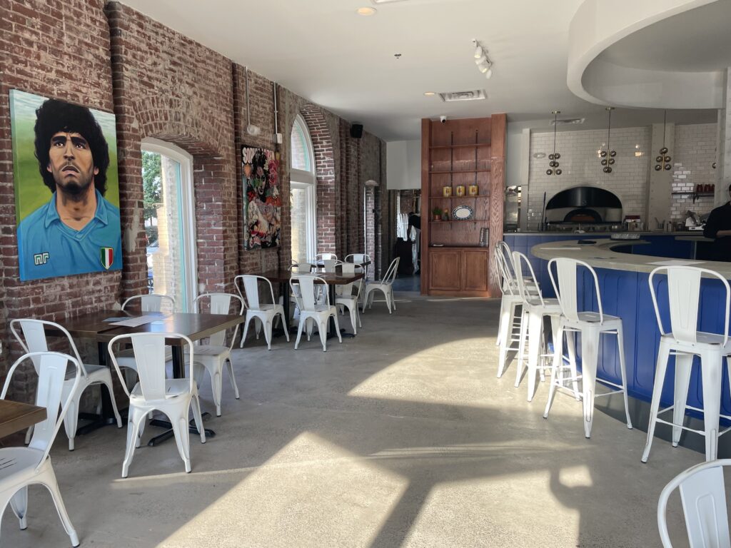 The interior of Sorellina with white chairs and a blue Italian tile bar.