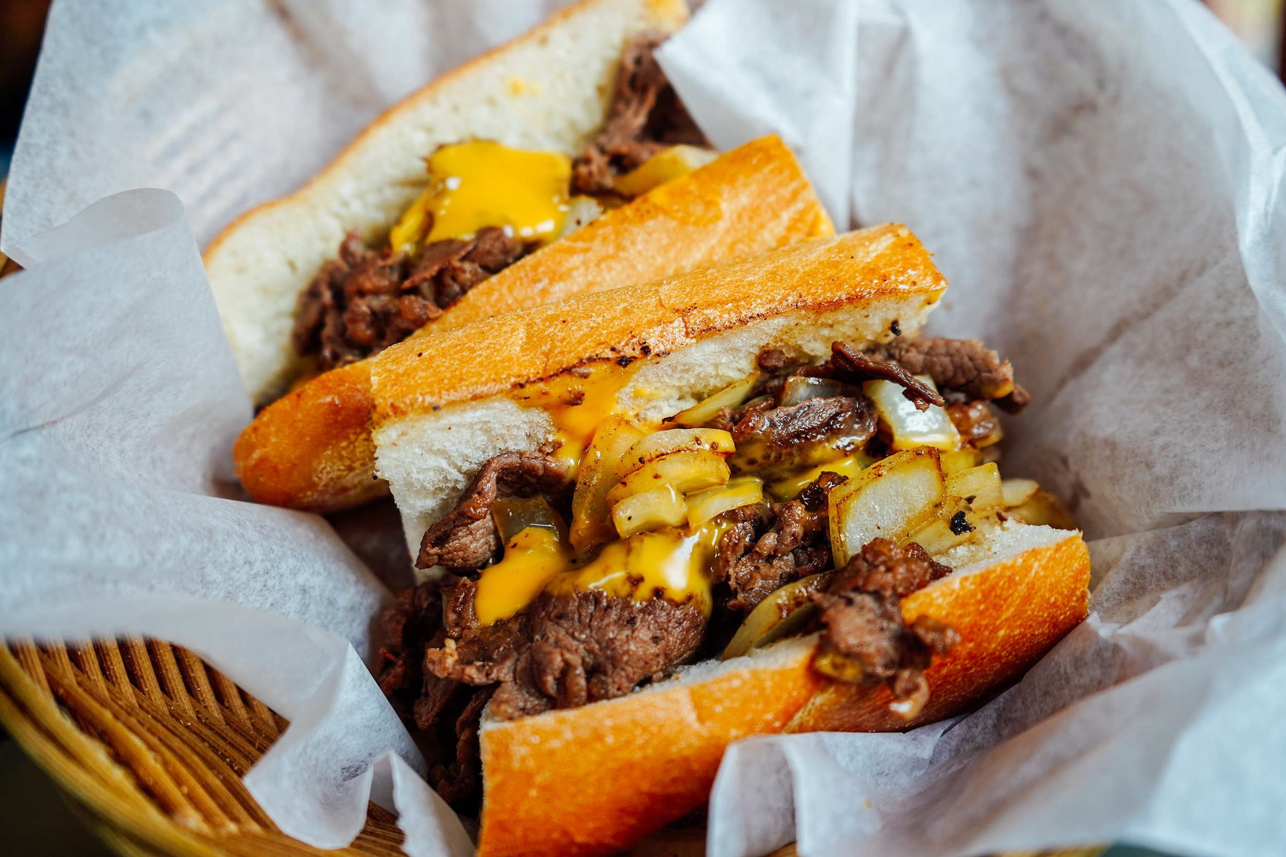 A cheesesteak is served in a basket.