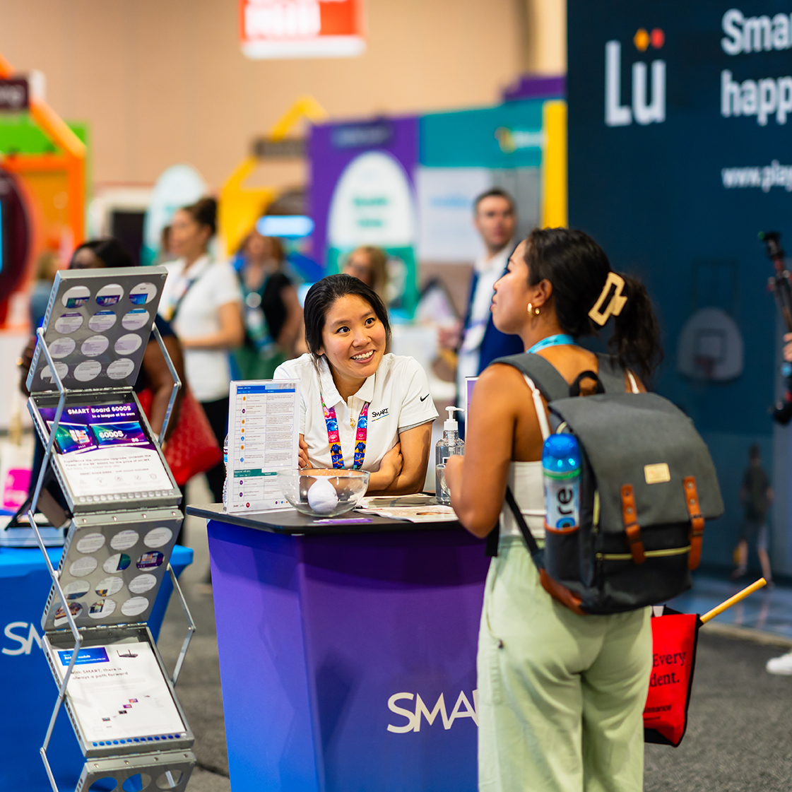 A convention attendee speaks with a person at a booth on the convention floor.