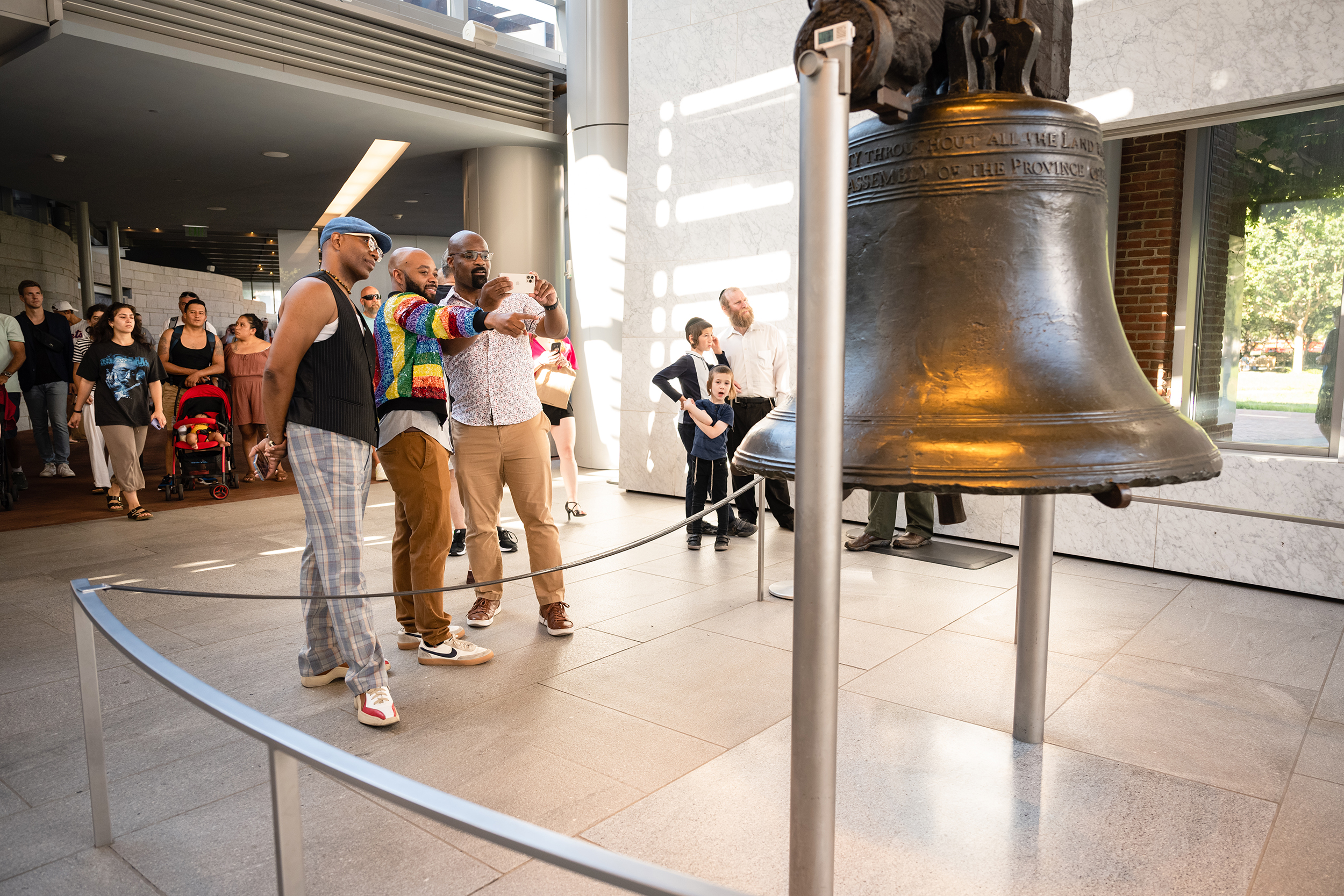 Three men take photos of the Liberty Bell.