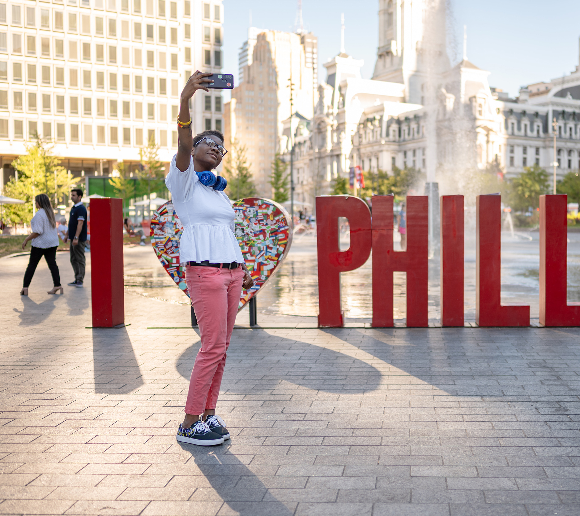 A person takes a selfie in front of a sign that says 
