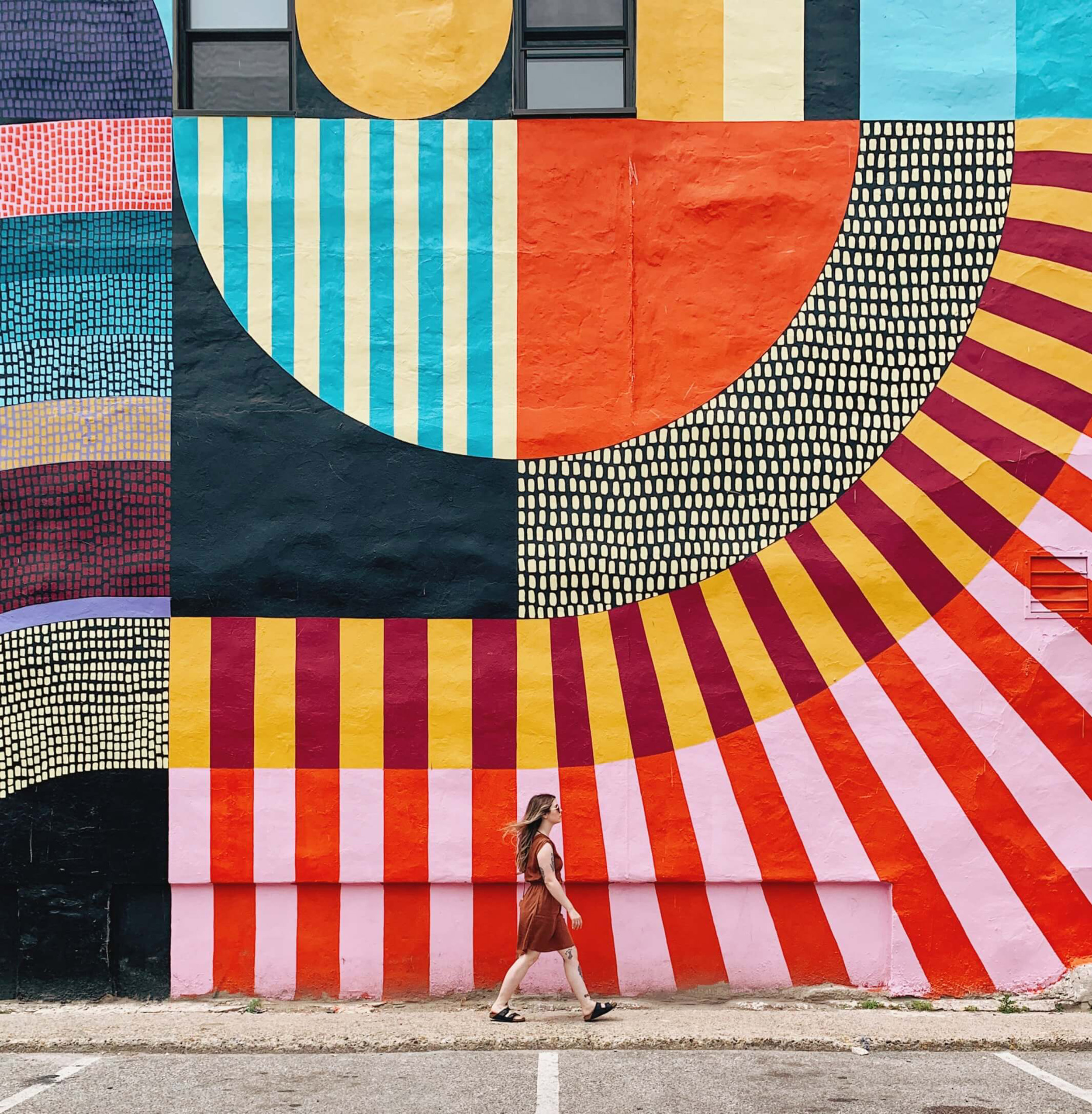 A person passes a colorful mural.