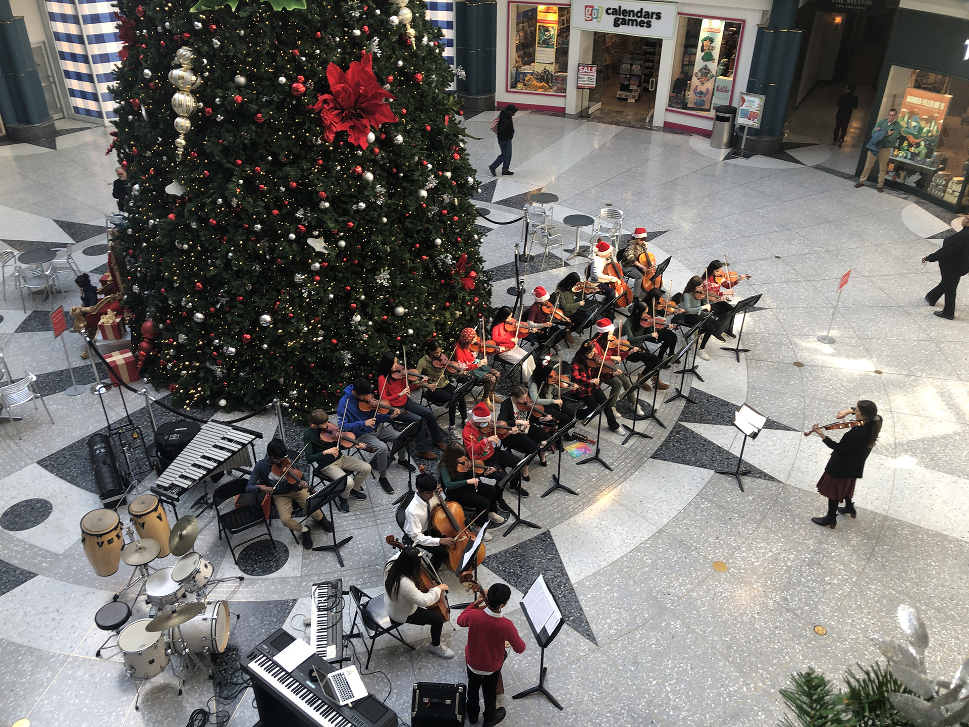 A group of students perform in front of a Christmas Tree.
