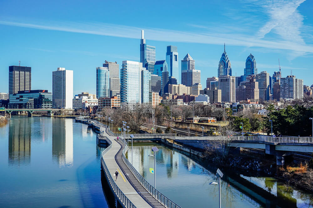 The Philadelphia skyline is shown. The sky above is a bright blue.
