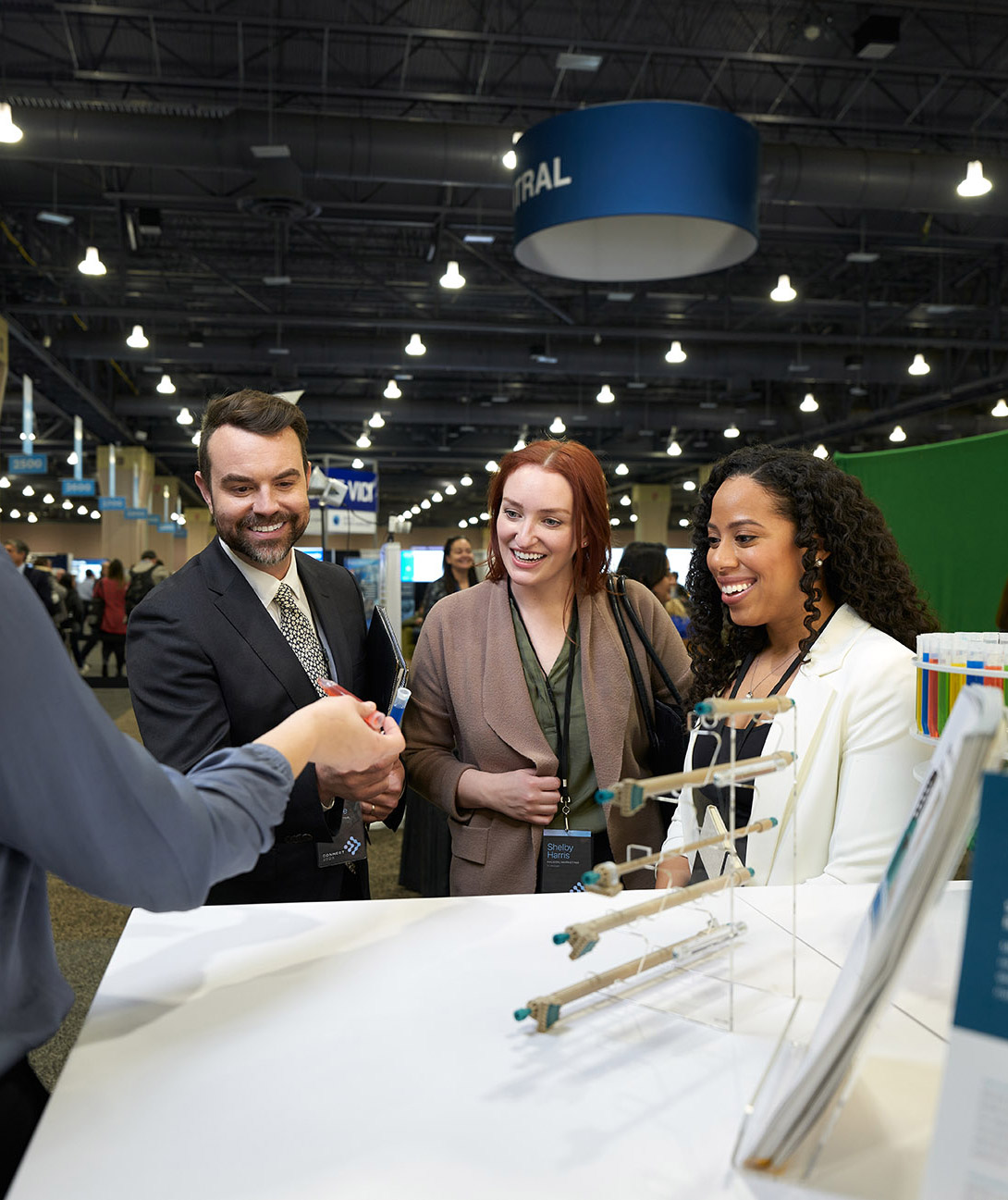 Three people speak to a person at a booth on the convention floor.