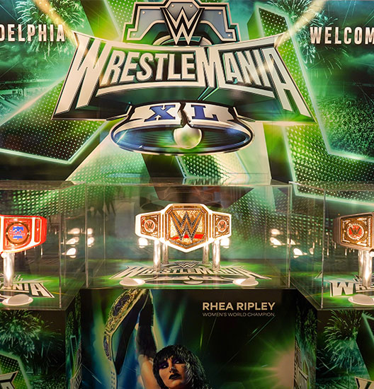 WrestleMania sign with WrestleMania belts in glass cases.