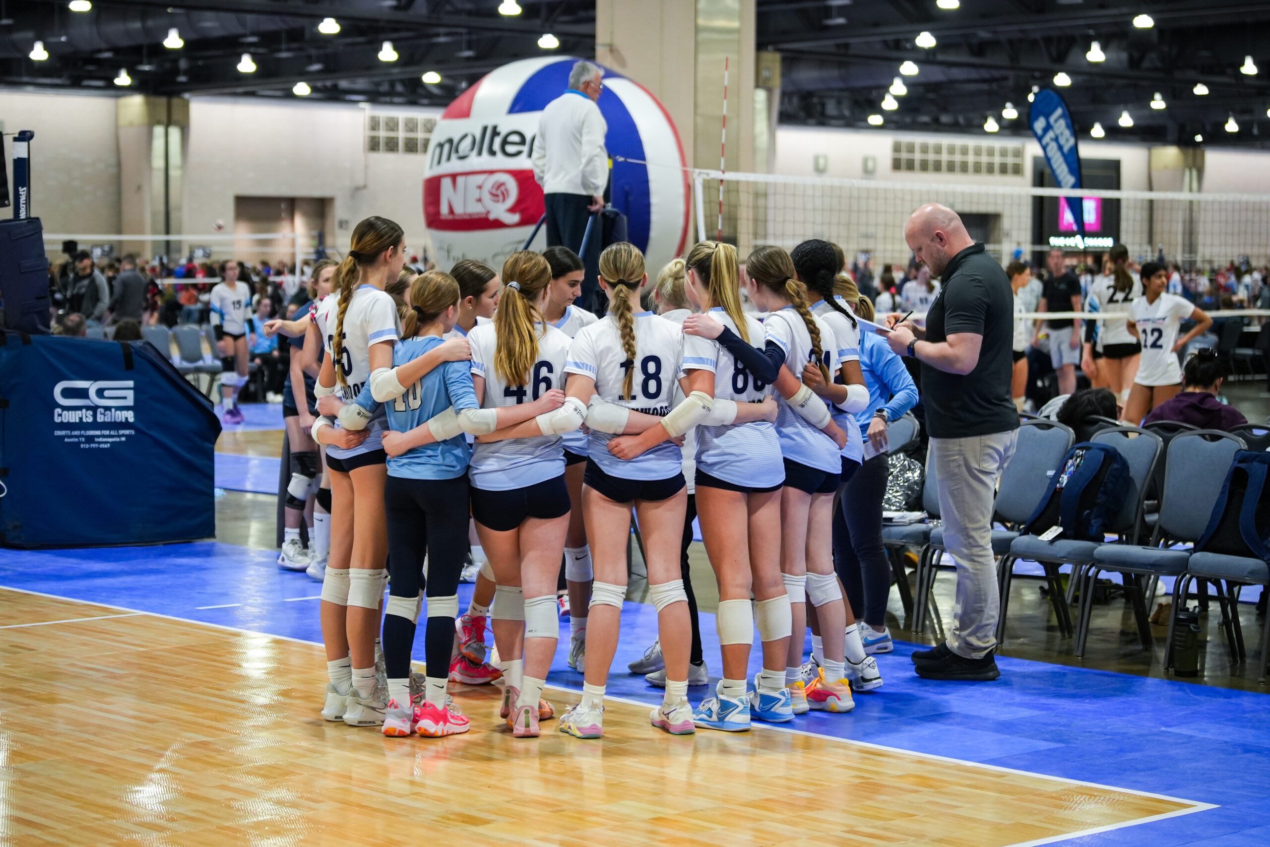 A team of volleyball players huddles up at NEW.