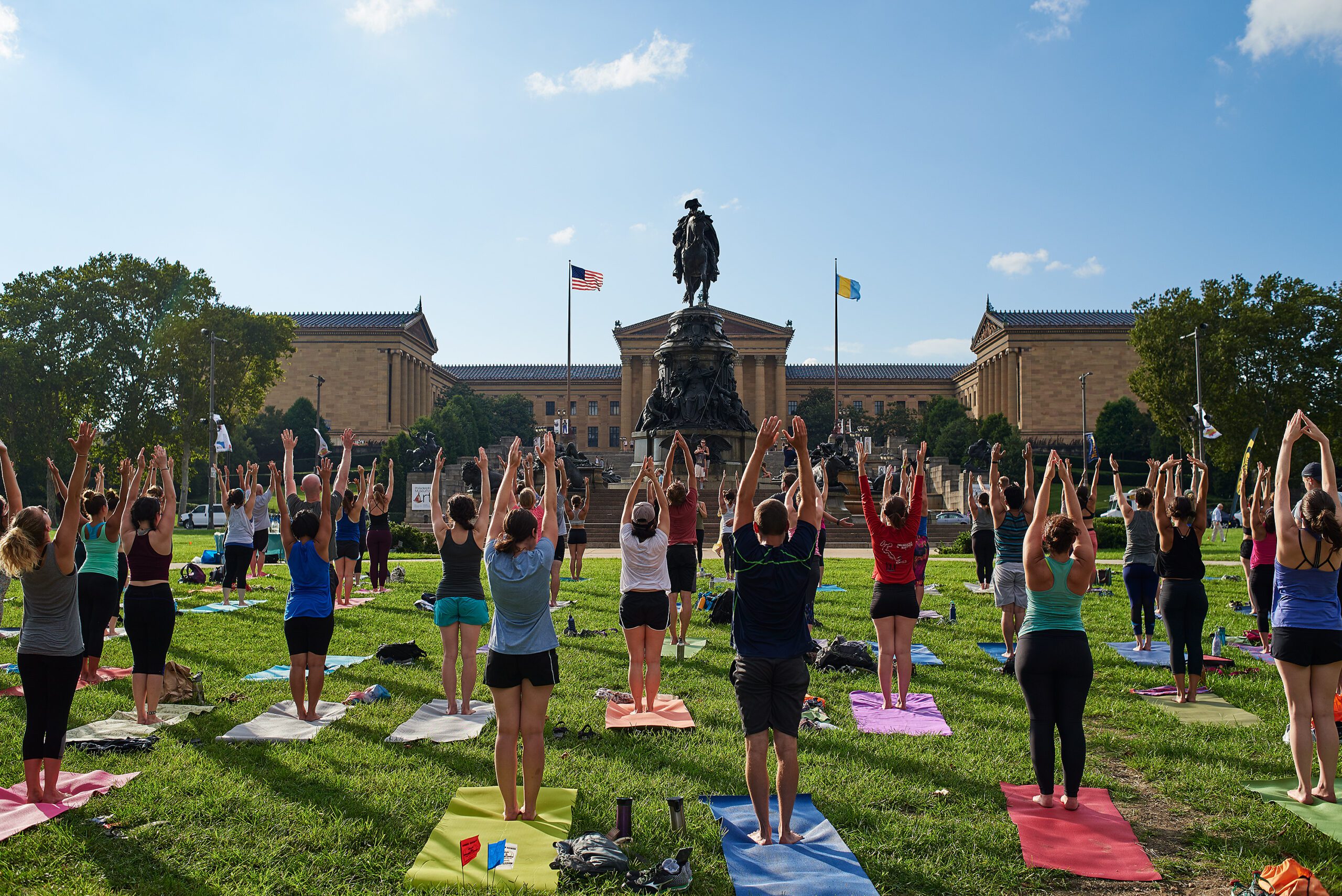 A group does yoga on a lawn in front of the Philadelphia Museum of Art.