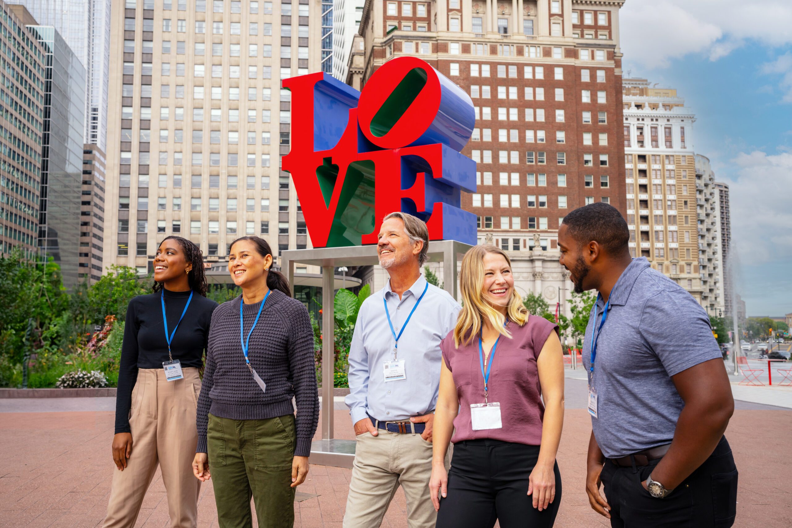 A group of meeting attendees laughing and walking in front of the LOVE statue.