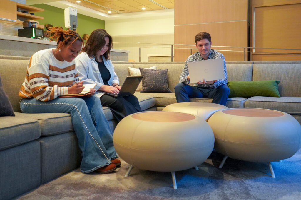 Three people on their laptops sitting on the couch in the lobby of the Element Hotel.