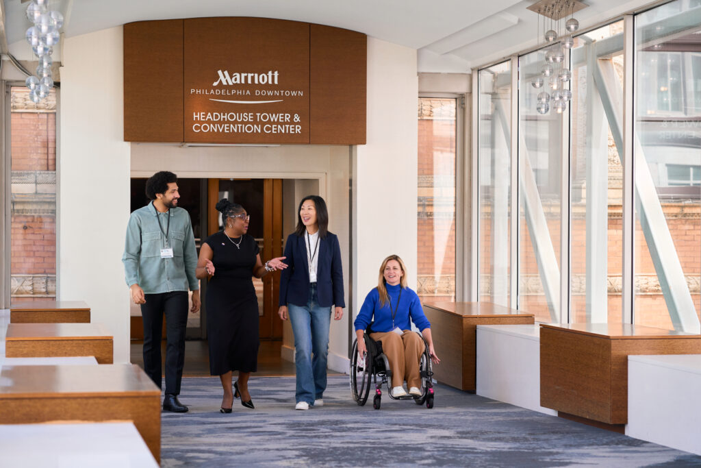Four people move across the skybridge from the Philadelphia Marriott Downtown to the Pennsylvania Convention Center.
