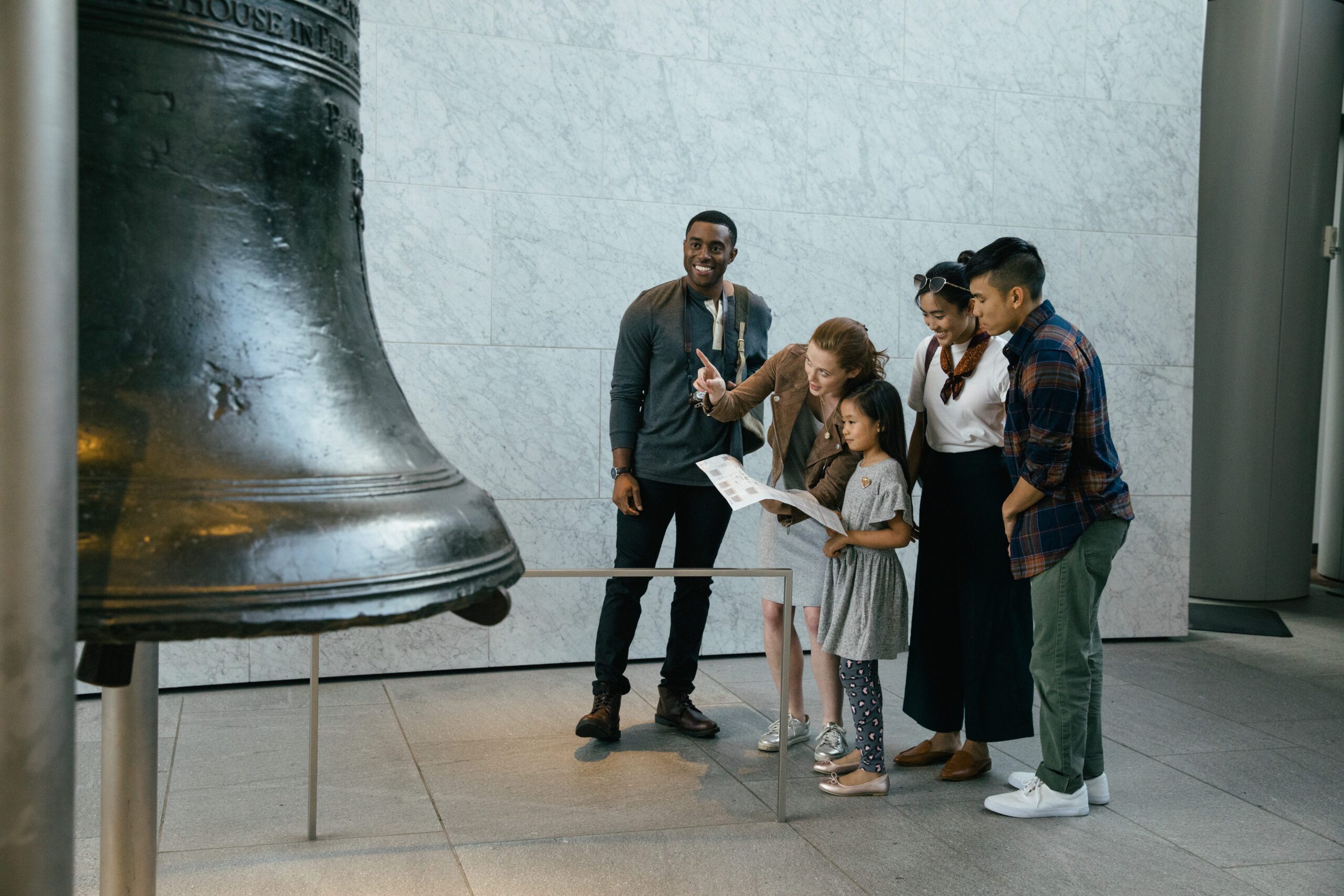 A family looks at a map and points at the Liberty Bell as they observe in the Liberty Bell Center.