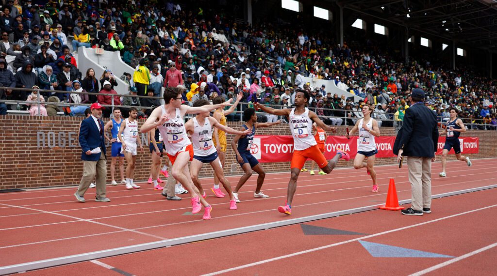 Runners pass off the baton in the middle of a race.