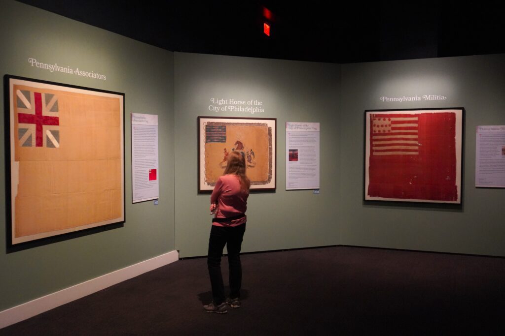 A woman looking at a flag at the "Banners of Liberty" exhibition at the Museum of the American Revolution.