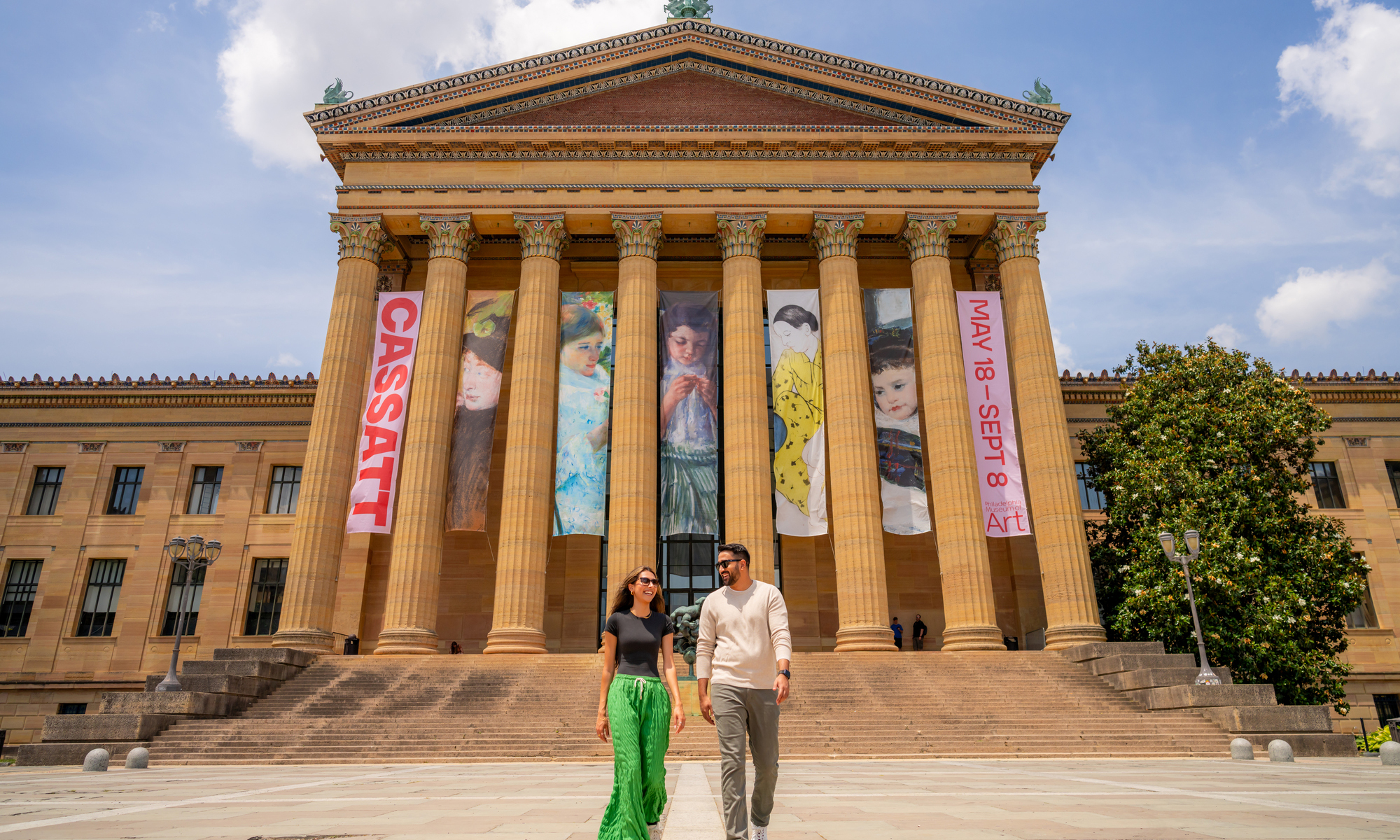 Two people walk in front of the Philadelphia Museum of Art