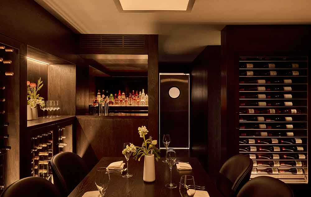 The inside of a nice restaurant with a table and wine cellar.