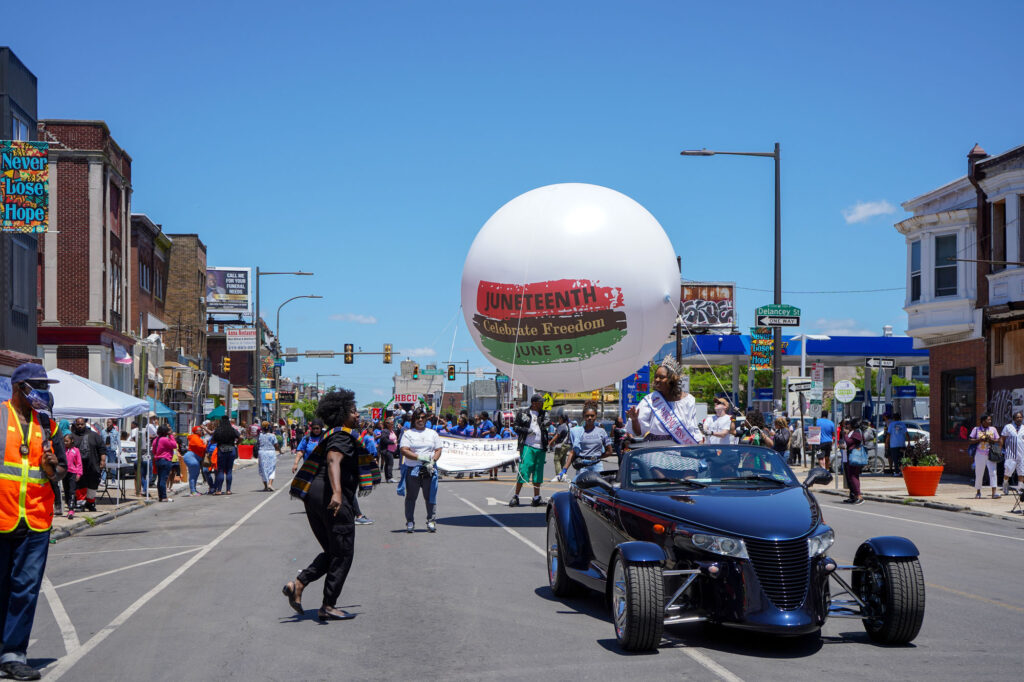 A crowned woman rides in a car for the Juneteenth parade 