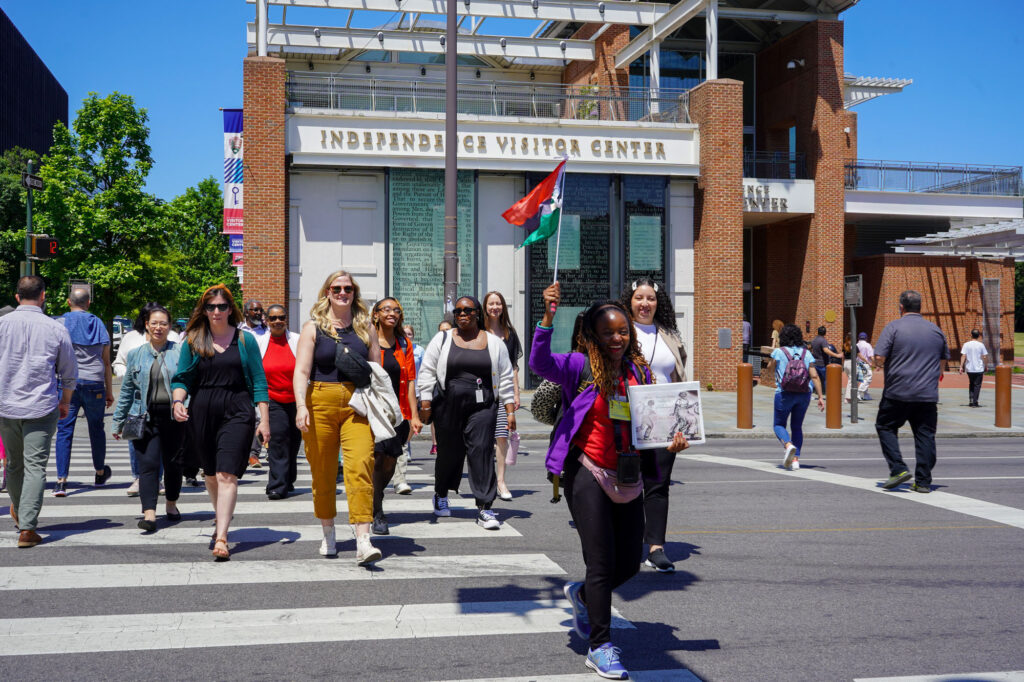 A guide leads a group of people in front of the Independence Visitors Center on the Black Journey Walking Tour.