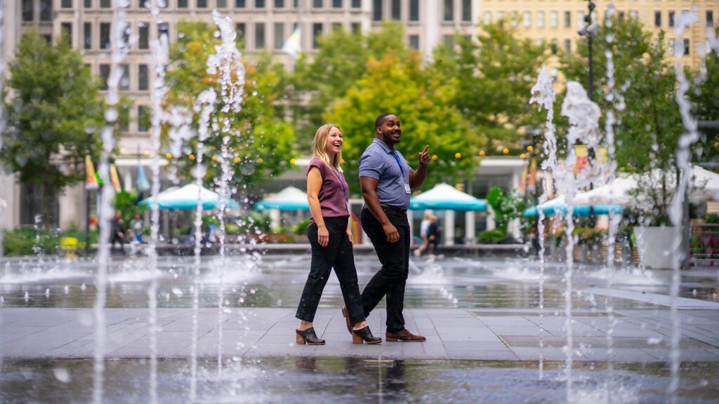 Two people walk by the fountains in Dilworth Park