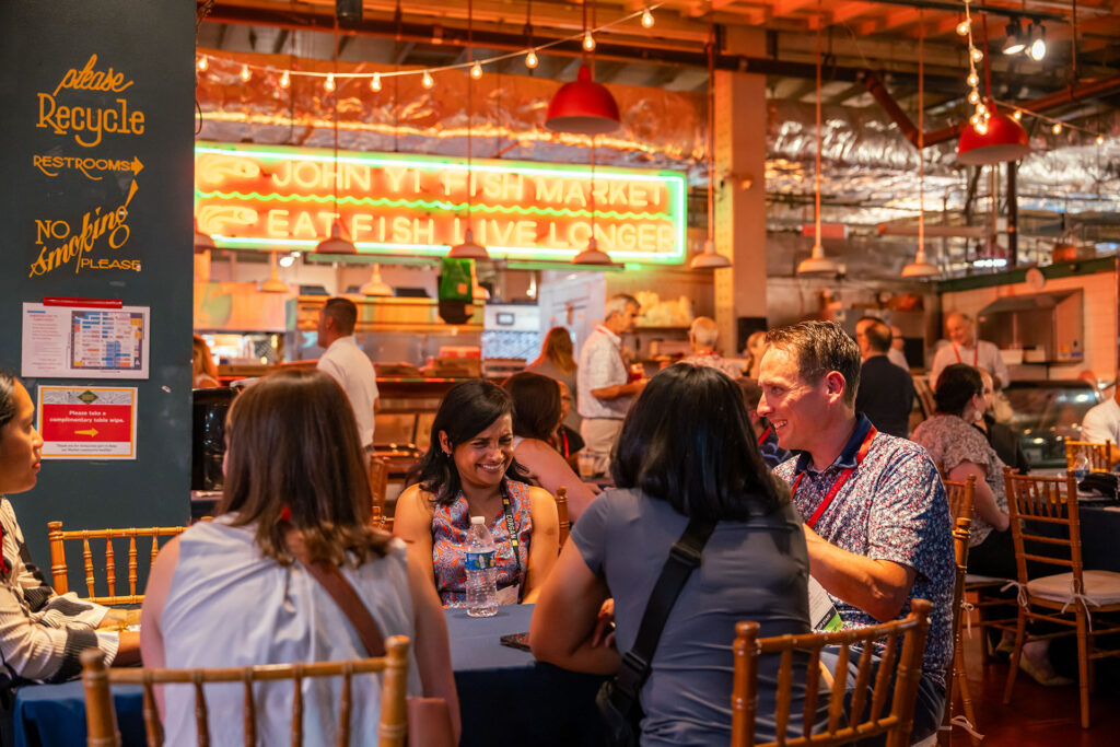 A group of people sit at an event table in Reading Terminal Market.