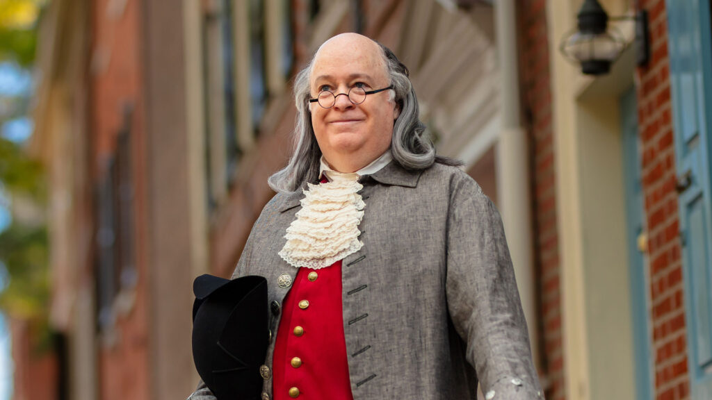 Photo of a Ben Franklin impersonator standing in front of a row of Philadelphia rowhomes.