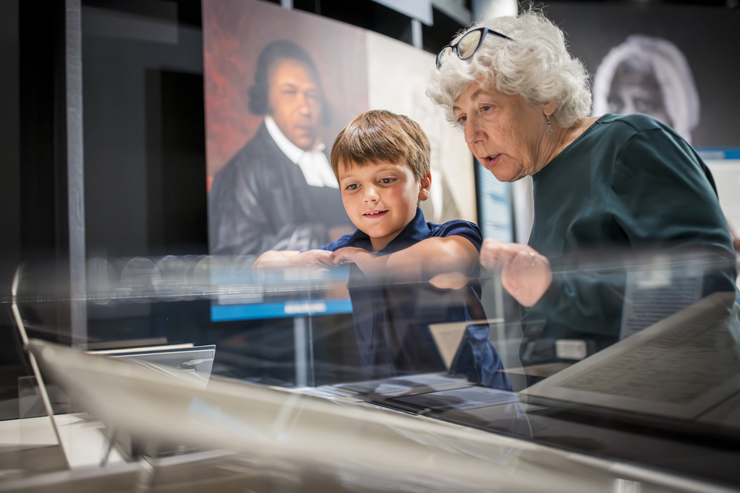 A woman and a child look over a Museum exhibit case